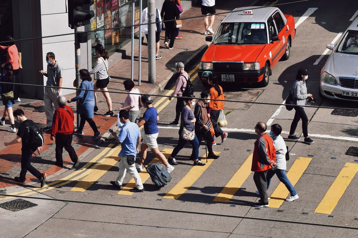 People crossing road with shadows on the ground on a sunny